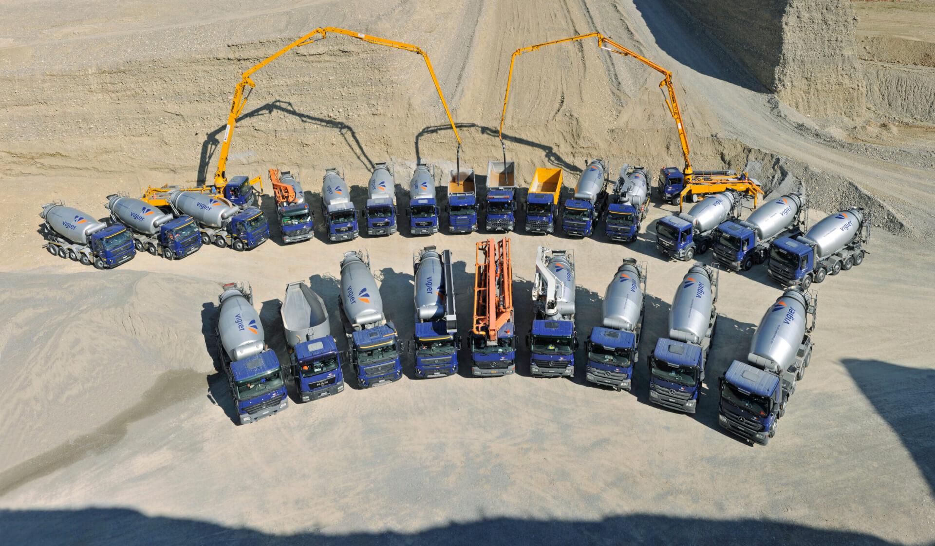Die Lastwagenflotte der Vigier Beton steht in einer Kiesgrube